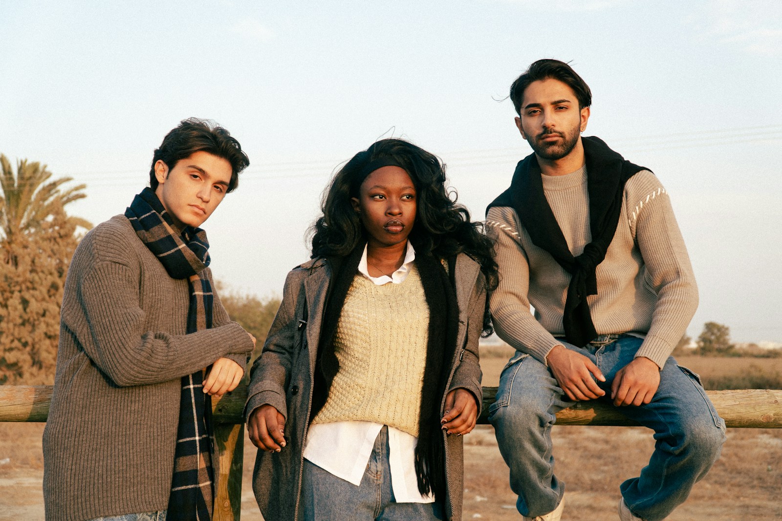 Three diverse young adults posing outdoors together outdoors.